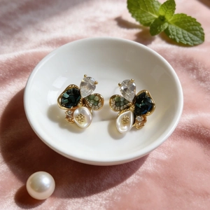 Vintage crystal pearl flower earrings with blue gems and white petals in a ceramic bowl