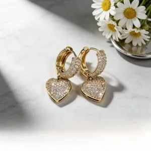 Dettaglio degli orecchini a cuore dorati con pavé di zirconi bianchi brillanti