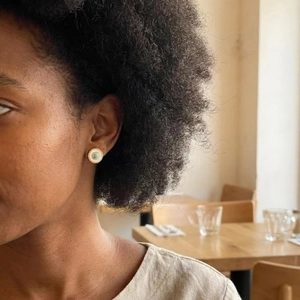 Vintage round turquoise and shell earrings shown worn by model in a warm cafe setting