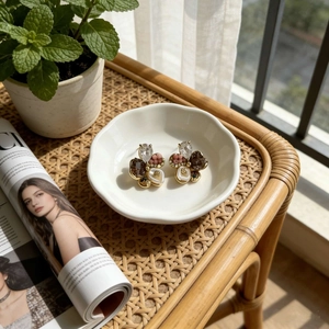Close-up of vintage flower earrings with crystals and pearls on a white ceramic dish
