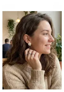 Détail de boucles d'oreilles camélia avec centre en perle portées dans un café