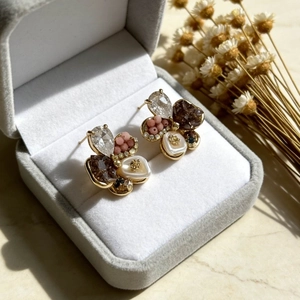 Macro shot of vintage irregular flower earrings with pearls and rhinestones in a gray box