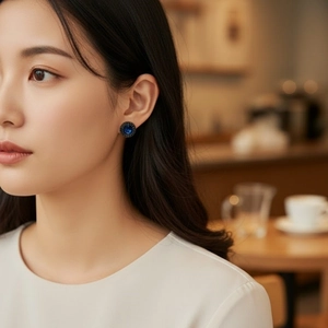 Elegant vintage dark blue zircon stud earrings worn by a model in a cozy cafe setting