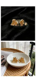 Detail of maple leaf stud earrings with amber crystals on black velvet and ceramic