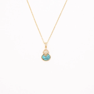 Détail d'un collier doré avec pendentif en turquoise et zircons étincelants sur fond blanc