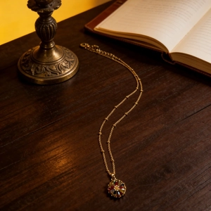 Vintage daisy necklace with colorful gems on a gold satellite chain over a retro wooden desk