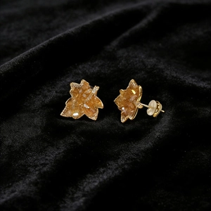 Caramel maple leaf stud earrings with gold plating and glittering resin on black velvet