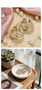 Detailed view of gold flower earrings with pearls on white ceramic and silk background