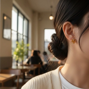 Elegant maple leaf earrings with gold plating and sparkling crystals on model in cafe