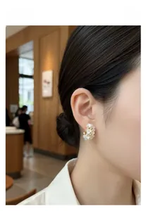 Detail of floral C-shaped pearl earrings on model for an elegant daily commuter look