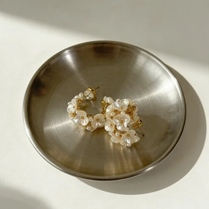 Elegant gold flower cluster earrings with mother of pearl and small pearls on metal tray