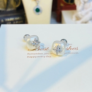 Detailed close-up of square pearl studs with sparkling silver starburst design