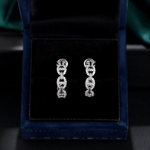 Boucles d'oreilles maillons pavées de diamants sur un écrin à bijoux en velours bleu