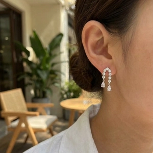 Élégantes boucles d'oreilles pendantes argentées avec pompons portées par un mannequin