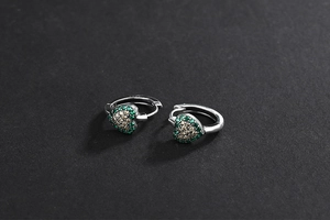 Détail macro des boucles d'oreilles cœur en argent S925 avec cristaux vert et champagne