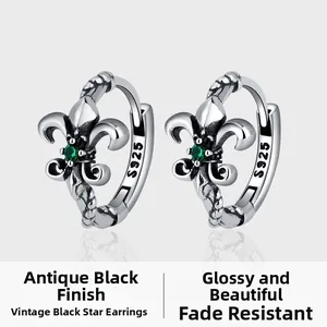 Detail of vintage 925 silver iris earrings with emerald zircon and oxidized finish