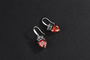 Detailed view of red heart crystal earrings with vintage silver crown setting craftsmanship
