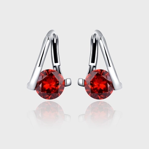 Detailed macro view of 925 sterling silver drop earrings with faceted red round stones