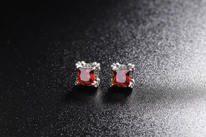Detailed close-up of square red gemstone earrings with vintage four-prong silver setting