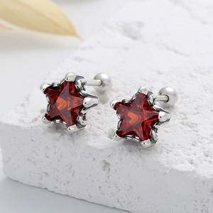 Détail macro de boucles d'oreilles étoile en argent 925 rétro avec zircone rouge et vis