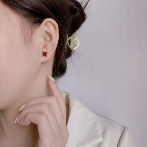 Close-up of square-cut red gemstone stud earrings with silver claw setting on model