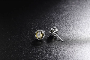 Dettaglio macro di orecchini d'argento con pietra gialla e castone a corona