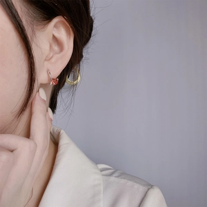 925 silver earring with round orange-red gemstone worn by a model in white blazer