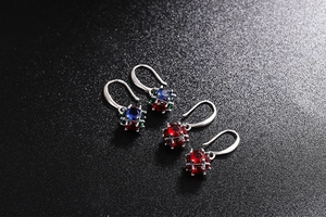 Detailed macro view of vintage silver earrings with vibrant red and blue zircon stones