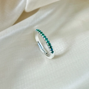 Close-up of 925 sterling silver adjustable ring with row of green emerald cubic zirconia