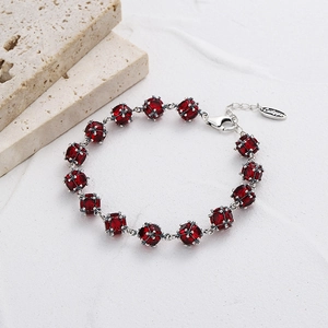 Détail d'un bracelet en pierres rouges avec monture argentée et logo de marque