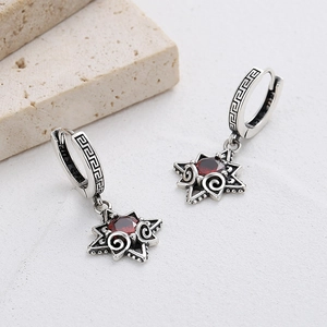 Macro detail of 925 silver star earrings with red zircon and greek key pattern