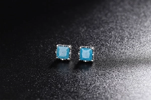 Macro detail of square blue zircon studs with silver beaded edges on black texture