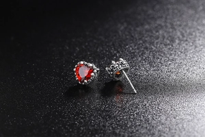 Vista ravvicinata di orecchini a cuore in argento 925 con zircone rosso e corona