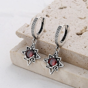Close-up of vintage 925 silver star earrings with red stone on textured stone base