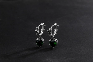 Close-up of S925 silver vintage earrings with green heart gems and gothic engravings