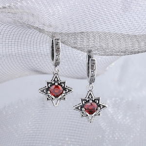 Detailed macro view of vintage S925 silver star earrings with a faceted red zircon stone