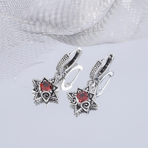 Macro shot of 925 silver star earrings with red stones and vintage Greek patterns
