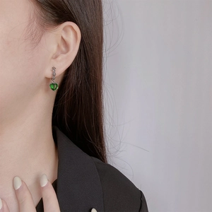 Close-up of S925 silver heart earring with green emerald zircon and iris flower detail