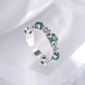 Macro detail of silver adjustable ring with relief patterns and green zircons