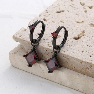 Détail macro de boucles d'oreilles gothiques en métal noir avec pierre rouge carrée