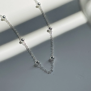 Détail du collier à billes en argent s925 sur un fond de pierre minimaliste