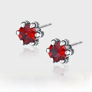 Macro detail of 925 silver stud earrings with vintage red zircon in six-claw flower setting