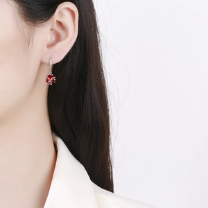 Elegant 925 sterling silver drop earrings with faceted red gemstone on female model