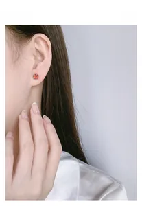 Detailed view of sterling silver claw-set orange zircon stud earrings on model's ear