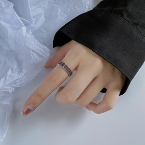 Modern silver geometric ring with micro-paved red and green zircons on a model's finger