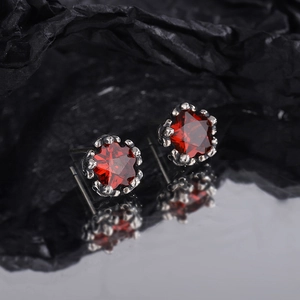 Vintage star earrings with red zircon and aged silver finish on a dark background