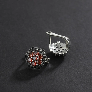 Macro shot of vintage S925 silver floral earrings with red garnet stones and black zircon