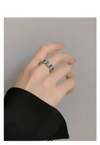Close-up of S925 silver ring with emerald and white zircon baguettes on woman's finger