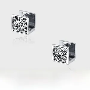Macro shot of vintage sterling silver square ear cuffs with floral vine carvings