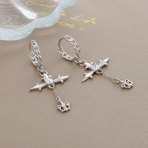 Macro shot of silver cross earrings with zircon studs and fleur-de-lis chain detail